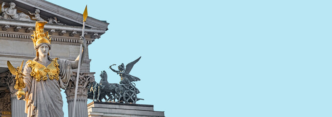 Athena Fountain (Pallas-Athene-Brunnen) in front of the Parliament during sunset, Vienna, Austria, at blue sky solid background with copy space. Concept of historical and religious heritage.