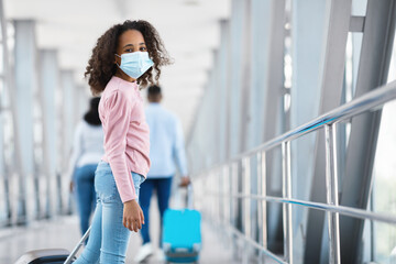 Wall Mural - Happy black girl looking back, standing in airport