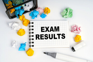 On the table is a basket, multi-colored paper and a notebook with the inscription - Exam Results