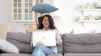 Wall Mural - Work from home with naughty kid: young mother businesswoman try to concentrate on business email in laptop with distracting little son hitting mom with pillow. Disobedient boy disturb freelancer mom