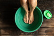 girl washes her feet in a green bowl on the wooden floor of the house, foot care