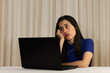 © Kharhem - Woman sitting in front of her laptop. staring at the screen, bored, sleepy, tired. Latin woman in front of her laptop without spirits.