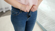 CLoseup of young woman upsets after fitting and trying to button up small jeans. Concept of excessive weight, obese female, dieting and overweight problems