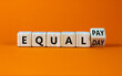 Equal pay day symbol. Turned the wooden cube and changed words equal pay to equal day. Beautiful orange background. Copy space. Business and equal pay day concept.