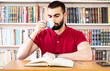 © Diya - Man reading a book and drinking in the library
