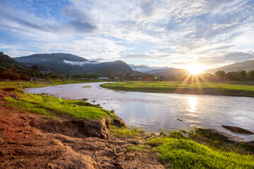 Mountain landscape, sunset, fog, clouds after the rain on the mountain, clear sky, river, light green grass Gives a cool and refreshing feeling in the background