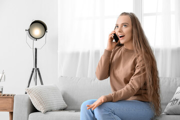 Sticker - Happy young woman talking by mobile phone at home