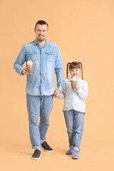 Wall Mural - Happy daughter and father with cups of hot cocoa on color background