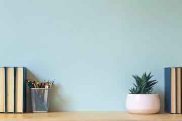 Home office desk table background. Empty wall with wooden table with stationery and books for work or study.