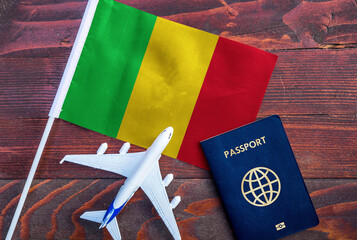 Flag of Mali with passport and toy airplane on wooden background. Flight travel concept 