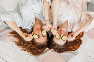 Wall Mural - two girls make homemade face and hair beauty masks. cucumbers for the freshness of the skin around t