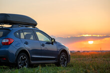 SUV Car With Roof Rack Luggage Container For Off Road Travelling Parked At Roadside At Sunset. Road Trip And Getaway Concept.
