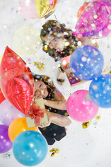 Two young and beautiful sexy Asian girls with colorful gift box dancing and playing with fun and happiness in a party with the bright color balloon in the background. Taken from a top-down angle.