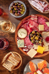 Wall Mural - Italian antipasti or Spanish tapas with wine. Gourmet charcuterie and cheese board, shot from above on a rustic background. Salmon sandwiches, salami, Parma ham, blue cheese. Mediterranean buffet