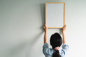 Asian woman hanging pictures on the wall