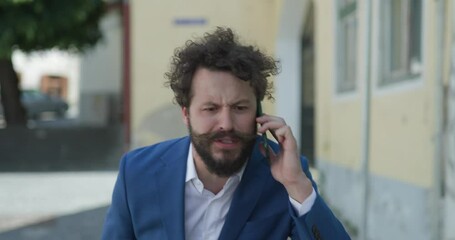 Sticker - upset unshaved guy in smart casual outfit talking on the phone, getting angry and closing the phone while walking outdoor