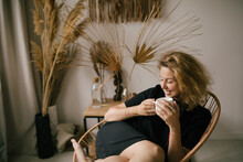 Young Woman Drinking Tea Or Coffee In A Cozy Room With Bohemian Interior.