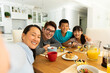 © WavebreakMediaMicro - Asian couple with son and daughter sitting at table eating together at home
