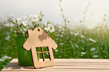 Wall Mural - on a wooden table a small decorative bucket with a bouquet of white flowers and a small house, concept