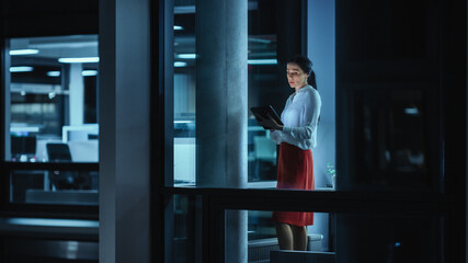 Poster - Shot from Outside: Businesswoman Working on a Tablet Computer in the Office. Manager Checking Emails while Standing by the Window. Employee Planning Financial Tasks and Business Development.