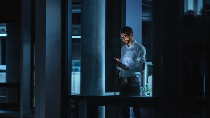 Poster - Shot from Outside: Businessman Working on a Digital Tablet Computer in the Office. Manager Checking Emails while Standing by the Window. Employee Planning Financial Tasks and Business Development.