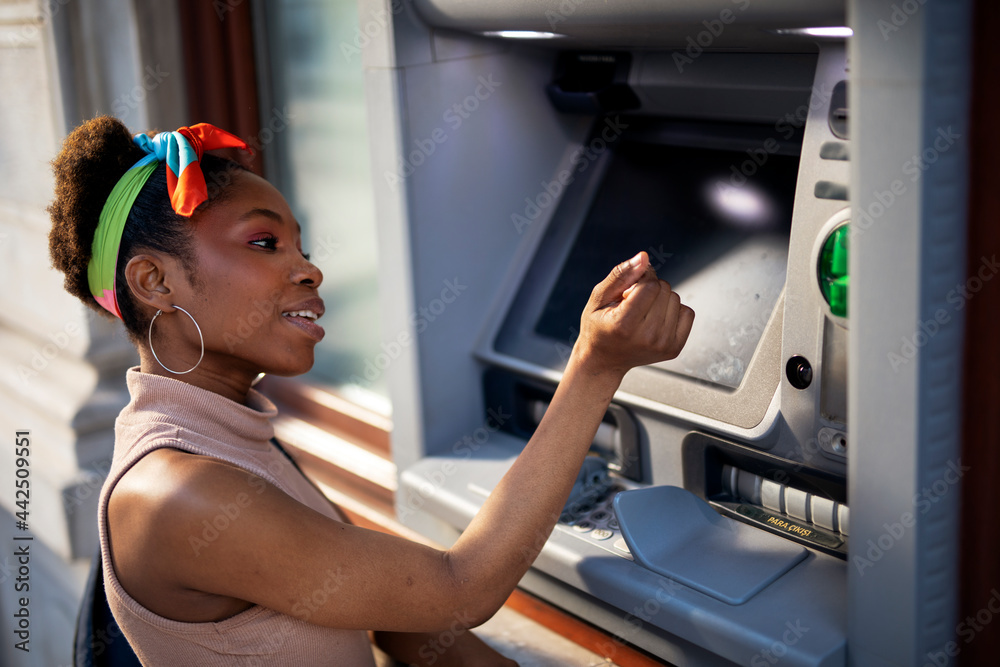 Beautiful african women using ATM machine. Attractive young woman ...