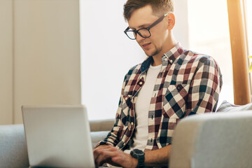 Young man working on computer, using laptop, studying online work from home, man typing on laptop computer on internet