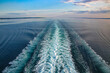 Wake of a ship across Ocean while sailing on a beautiful day. Purple and blue light reflecting on the sea and waves. Cruising the Baltic, North Sea and fjords, Northern Europe.