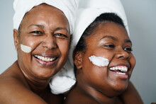 African Mother And Daughter Doing Beauty Treatment At Home Using Skin Mask - Body Care And Family Concept - Focus On Girl Mouth