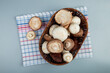 top view of fresh mushrooms in a wicker basket on plaid napkin on light blue background