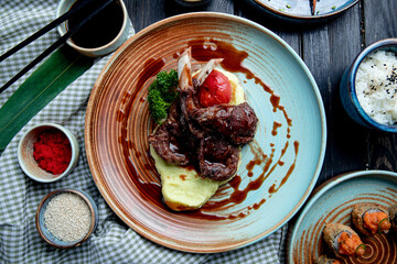 Wall Mural - top view of mashed potatoes with roasted lamb chops and vegetables with soy sauce on a plate on wooden background