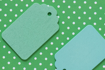 two retro wooden pastel green and blue merchandise tags or labels isolated on white and green polka dot patterned paper background