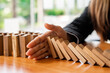 © crizzystudio - A businesswoman blocks a falling wooden block like a domino. It is like stopping business risks with a strategy. and project management the best of the business