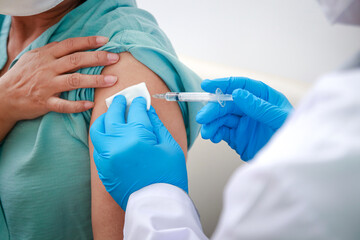 Close-up portrait of an elderly woman receiving coronavirus vaccination from a male doctor wearing blue gloves To strengthen the immune system to prevent infection. Elderly Vaccination