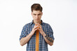 © Cookie Studio - Serious evil genius guy, young man scheming, making plan, looking cunning and thoughtful, master mind idea, steeple fingers while thinking, standing against white background