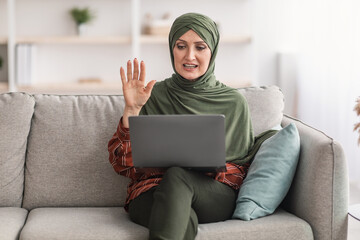 Wall Mural - Muslim Lady In Hijab Video Calling Waving To Laptop Indoor