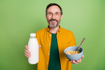 Poster - Photo of mature happy positive man hold hands milk food breakfast smile isolated on green color background