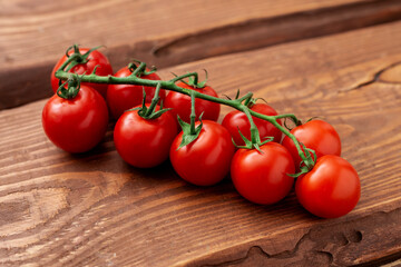 Wall Mural - Cherry tomatoes on a wooden background. Fresh tomato branch. Vegetarian food.