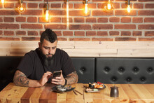 Man Using Smartphone In Sushi Bar