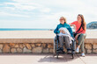 © ADDICTIVE STOCK - Daughter sitting with aged mother in wheelchair on embankment