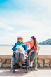 © ADDICTIVE STOCK - Daughter sitting with aged mother in wheelchair on embankment