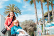 © ADDICTIVE STOCK - Aged mother in wheelchair and adult daughter walking in city