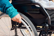 © ADDICTIVE STOCK - Anonymous senior woman in wheelchair riding along wooden promenade