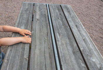 Close up view of child's arms on wooden table on playground.