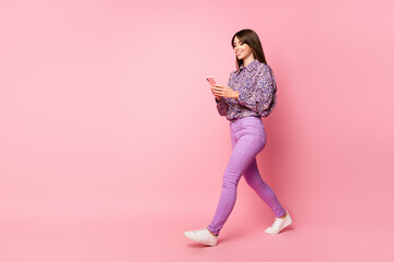 Sticker - Full size profile side photo of young happy cheerful smiling girl go walk using smartphone isolated on pink color background