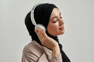 Wall Mural - Portrait of young arabian girl in hijab and headphones