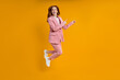 © alfa27 - Successful business female in pink suit jumping pinting index finger at side, isolated on yellow background, shopping. portrait. copy space for advertisement