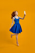 © alfa27 - Full length body size photo of stylish trendy redhead woman taking selfie jumping in blue dress isolated yellow studio background, portrait. copy space