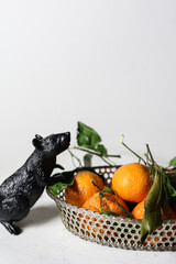 Wall Mural - mandarins in a basket with black rat mouse against white