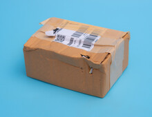 Damaged Cardboard Box With Hole On Blue Background,cardboard Box Destroyed In Shipping